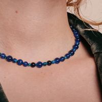 la modella indossa: Collana Blue Beads di RIMA, composta da splendide perline in pietra naturale dalle tonalità variabili del blu, estremamente lucide e impreziosite da venature e sfumature più scure.