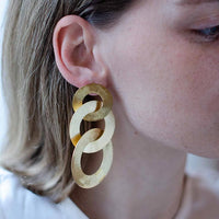 Close-up of a blonde woman wearing gold coated handmade bronze earrings
