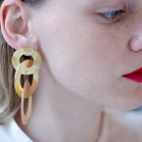 Close-up of a blonde woman wearing gold coated handmade bronze earrings