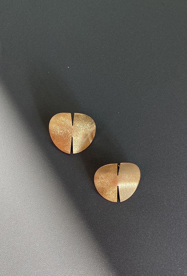Close-up of a sleek, gold covered sterling silver earring with a polished finish