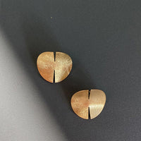 Close-up of a sleek, gold covered sterling silver earring with a polished finish