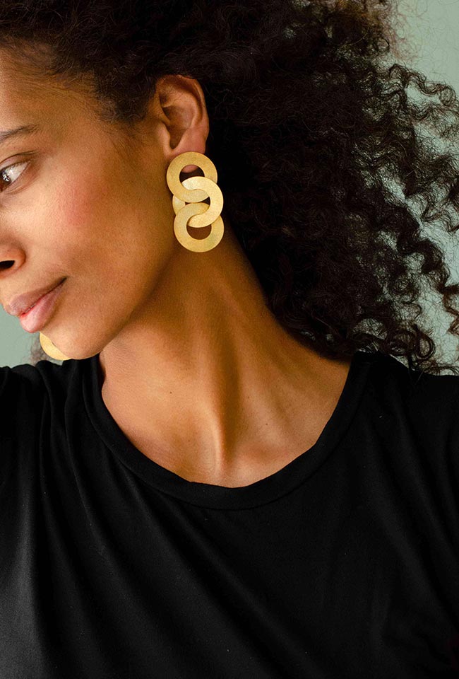 Close-up of a woman with curly hair wearing Gold coated handmade bronze earrings