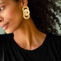 Close-up of a woman with curly hair wearing Gold coated handmade bronze earrings