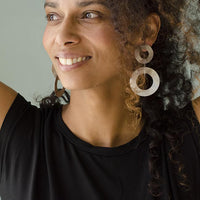 Close-up of a woman with curly hair wearing coated handmade bronze earrings