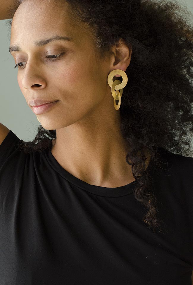 Close-up of a woman with curly hair wearing Gold coated handmade bronze earrings