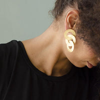 Close-up of a woman with curly hair wearing Gold coated handmade bronze earrings