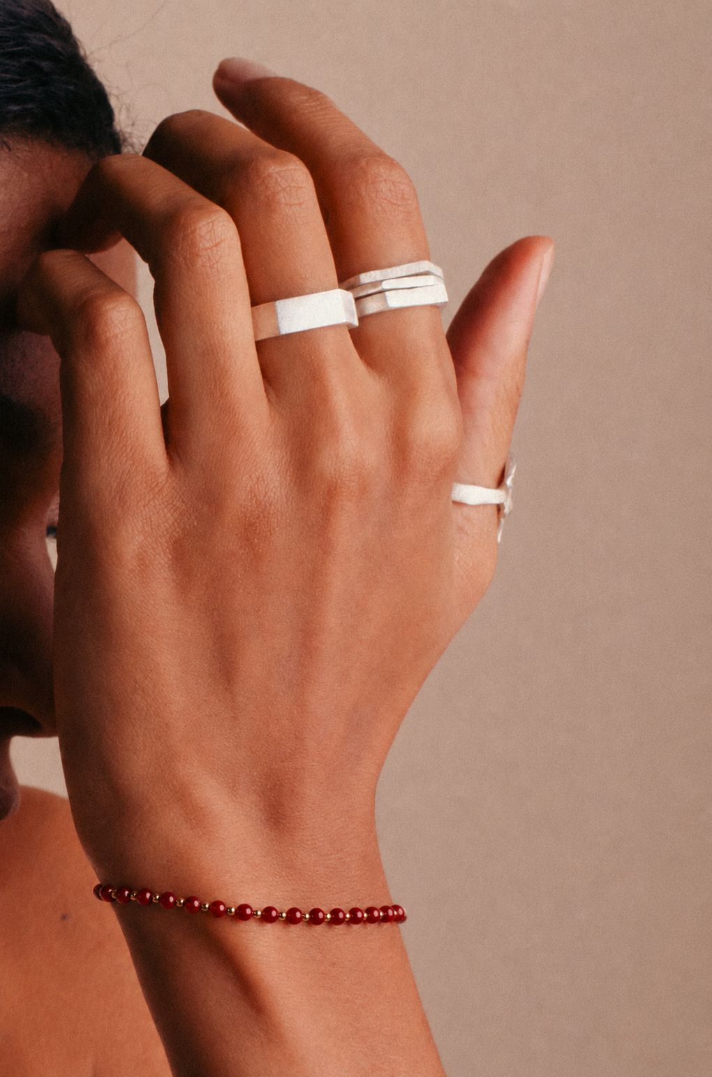 la modella indossa al polso: Bracciale Bordeaux Beads di RIMA: Questo bracciale è composto da splendide e piccolissime perline in pietra naturale dalle tonalità bordeaux, impreziosite dall'alternanza di perline dorate ancora più minute. 