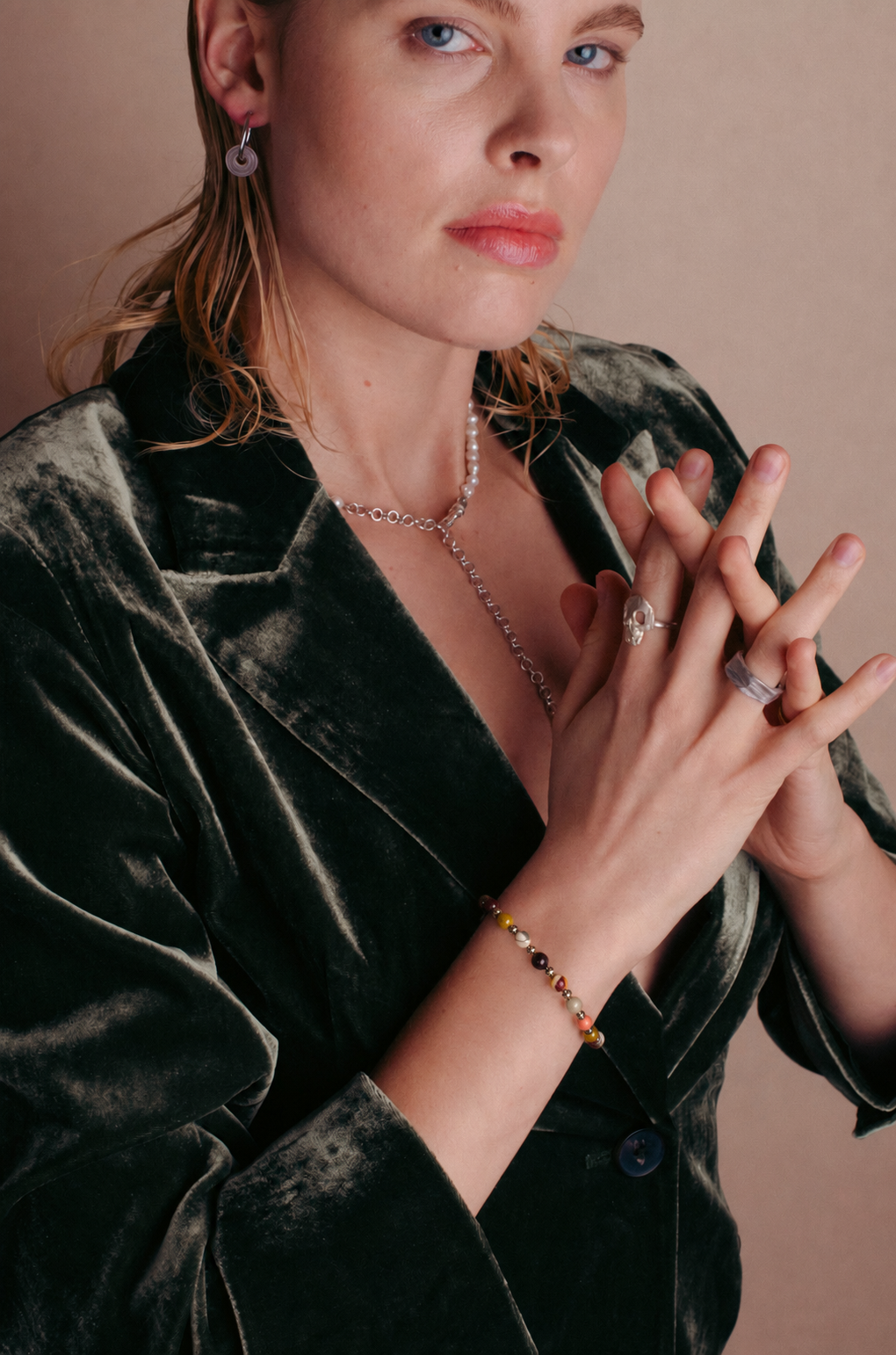 la modella indossa al polso il: Bracciale Red-Yellow Beads di RIMA:  è composto da splendide perline in pietra naturale dalle tonalità variabili dal rosso al giallo, impreziosite da sfumature e venature che vanno dall'avorio al violaceo. Il design è rifinito da ulteriori perline argentate e lucenti, disposte in modo da suddividere finemente le varie pietre.