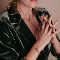 la modella indossa al polso il: Bracciale Red-Yellow Beads di RIMA:  è composto da splendide perline in pietra naturale dalle tonalità variabili dal rosso al giallo, impreziosite da sfumature e venature che vanno dall'avorio al violaceo. Il design è rifinito da ulteriori perline argentate e lucenti, disposte in modo da suddividere finemente le varie pietre.