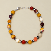 Bracciale Red-Yellow Beads di RIMA:  è composto da splendide perline in pietra naturale dalle tonalità variabili dal rosso al giallo, impreziosite da sfumature e venature che vanno dall'avorio al violaceo. Il design è rifinito da ulteriori perline argentate e lucenti, disposte in modo da suddividere finemente le varie pietre.