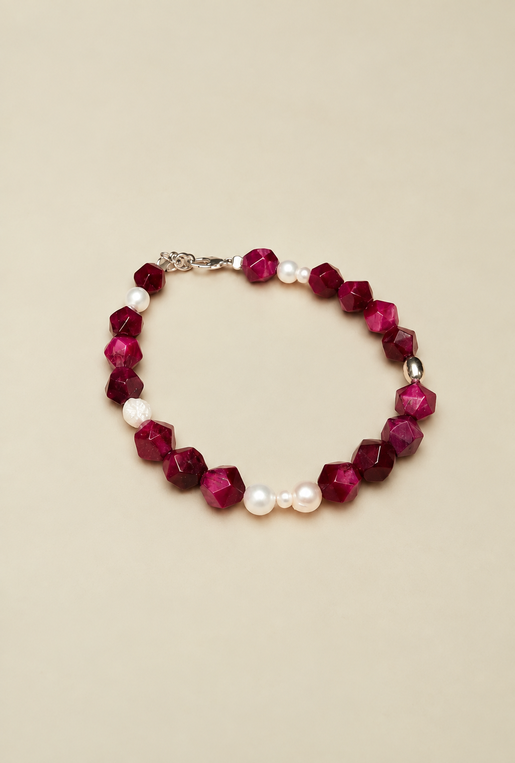Bracciale Pink & Pearls di RIMA; con perline di pietra rosa scuro, dalle forme squadrate e spigolose, e perle naturali dalle linee imperfette, tondeggianti e ricche di naturalezza.  completato dall'iconica perlina incisa con il marchio RIMA.
