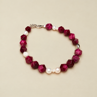 Bracciale Pink & Pearls di RIMA; con perline di pietra rosa scuro, dalle forme squadrate e spigolose, e perle naturali dalle linee imperfette, tondeggianti e ricche di naturalezza.  completato dall'iconica perlina incisa con il marchio RIMA.
