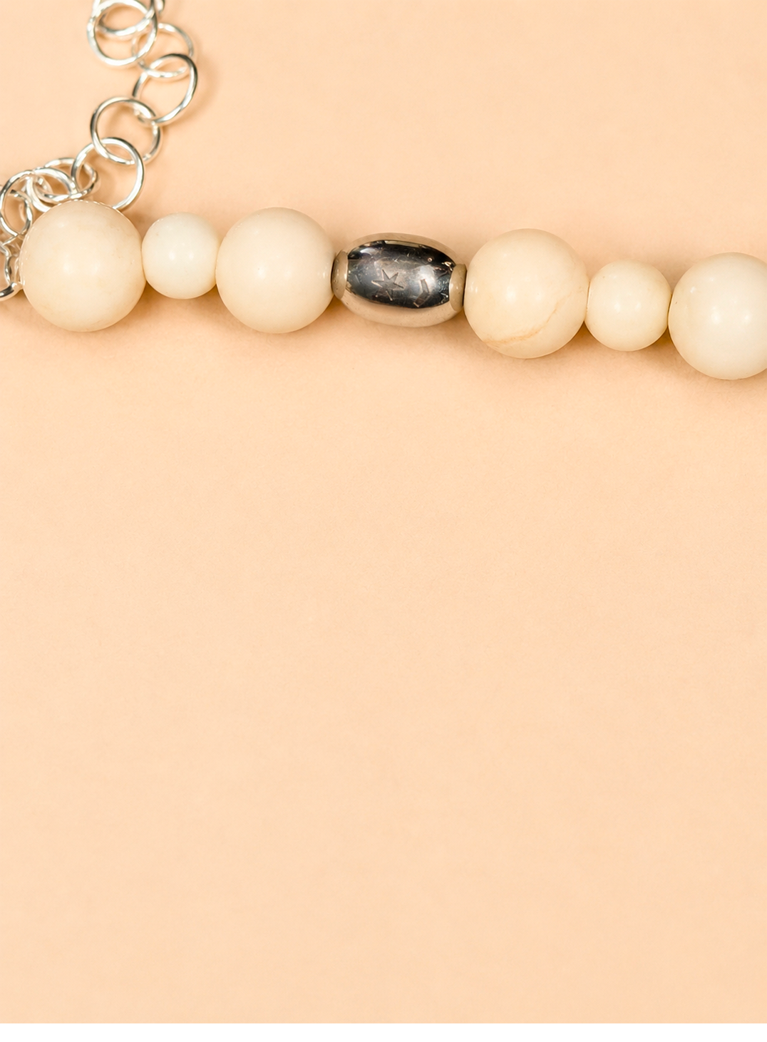 scatto ravvicinato della Collana White Beads di RIMA:

-splendide pietre dalle tonalità avorio panna, impreziosite da venature
-iconica perlina incisa con il marchio RIMA.