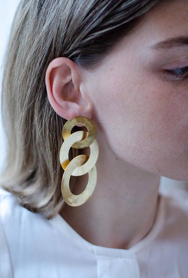 Close-up of a blonde woman wearing gold  coated handmade bronze earrings