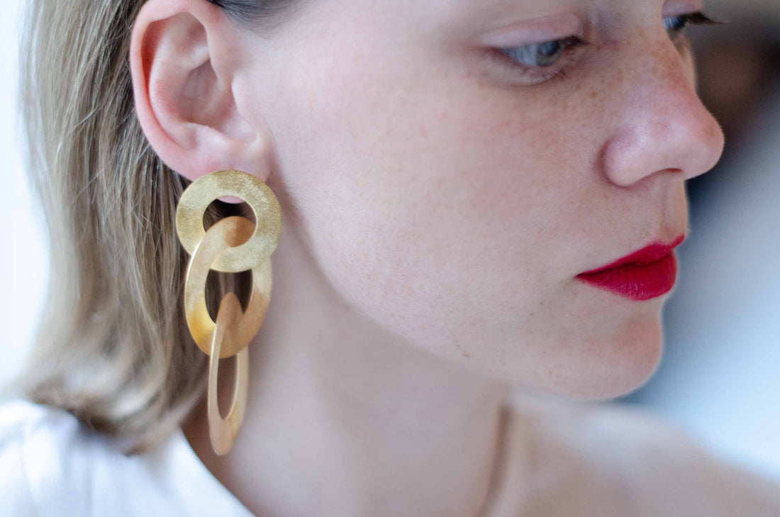 Close-up of a blonde woman wearing gold  coated handmade bronze earrings