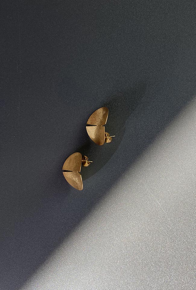 Close-up of a sleek, gold covered sterling silver earring with a polished finish