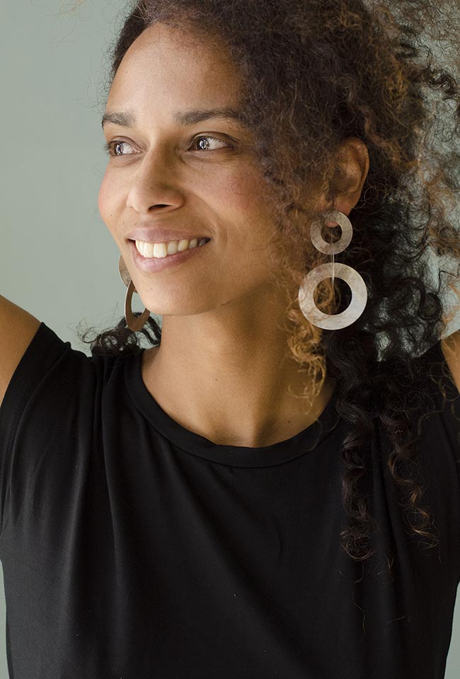 Close-up of a woman with curly hair wearing coated handmade bronze earrings