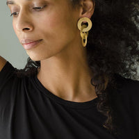 Close-up of a woman with curly hair wearing Gold coated handmade bronze earrings
