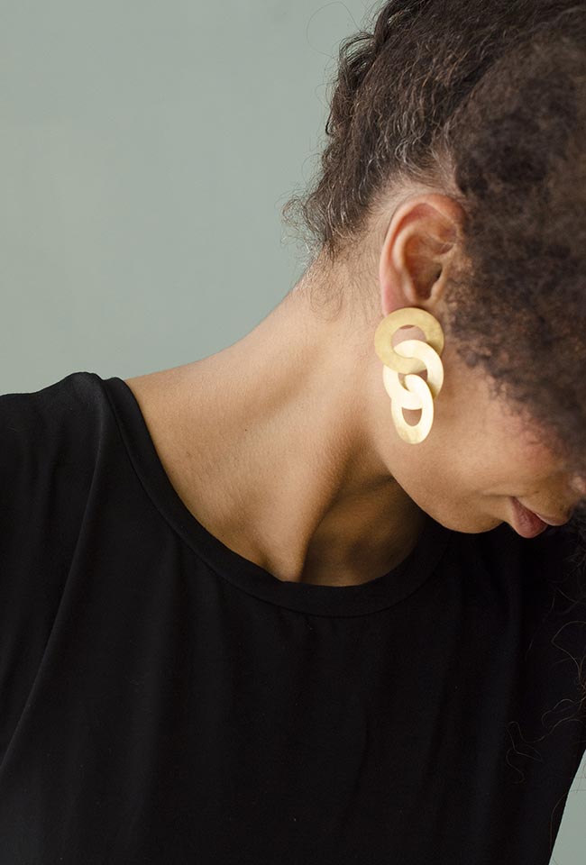Close-up of a woman with curly hair wearing Gold coated handmade bronze earrings