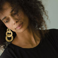 Close-up of a woman with curly hair wearing coated handmade bronze earrings